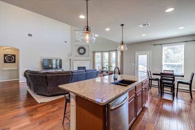 kitchen with visible vents, dark wood-type flooring, stainless steel dishwasher, a glass covered fireplace, and a sink