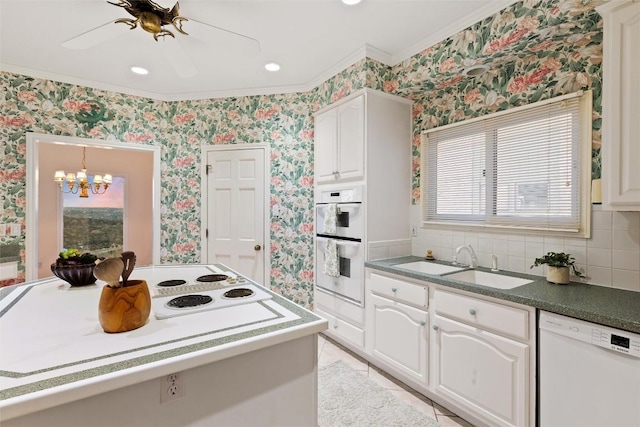 kitchen featuring a sink, tasteful backsplash, white appliances, white cabinets, and wallpapered walls