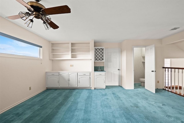 interior space with a sink, baseboards, light carpet, and a ceiling fan