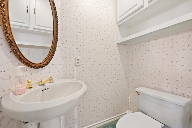 bathroom featuring wallpapered walls, toilet, and a sink