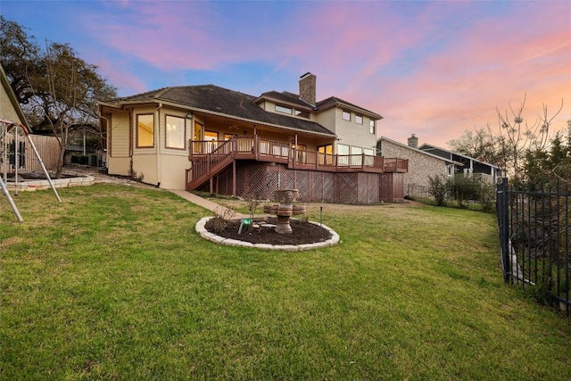 back of property at dusk with a lawn, a deck, a fenced backyard, stairs, and a chimney