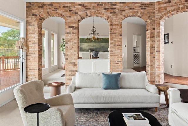 unfurnished living room with arched walkways, brick wall, baseboards, and an inviting chandelier