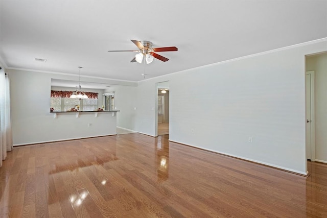 unfurnished living room with wood finished floors, baseboards, visible vents, ornamental molding, and ceiling fan with notable chandelier