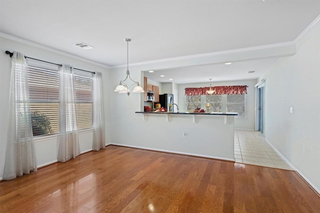 interior space featuring light wood finished floors, a kitchen breakfast bar, stainless steel appliances, and a peninsula