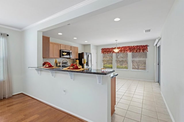 kitchen featuring stainless steel appliances, a peninsula, visible vents, and a breakfast bar