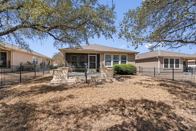 rear view of property featuring stucco siding, fence, and a sunroom