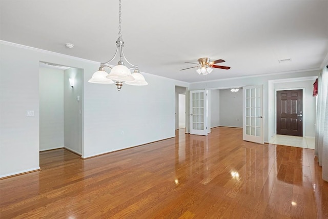 unfurnished room with wood finished floors, baseboards, ornamental molding, ceiling fan, and french doors