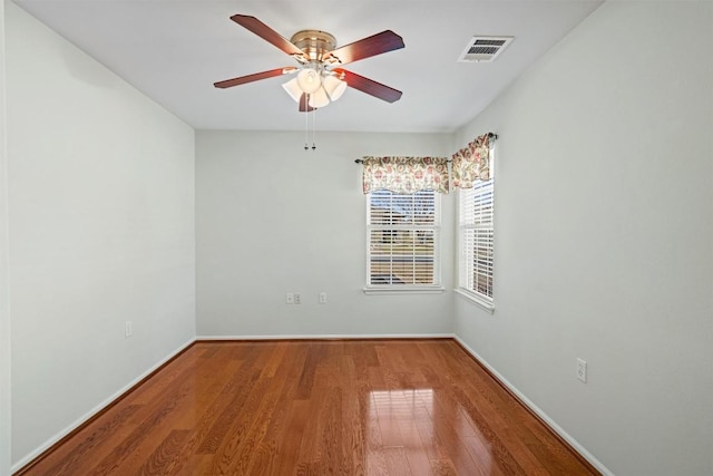 empty room with visible vents, baseboards, wood finished floors, and a ceiling fan