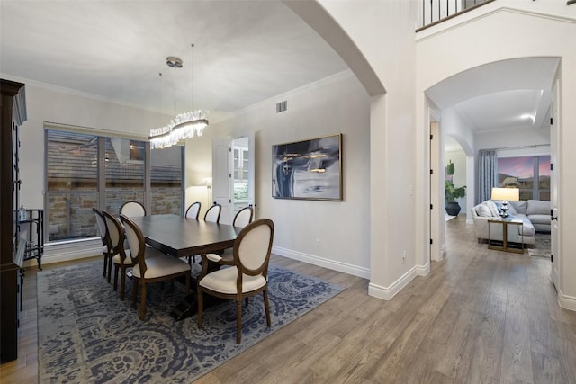 dining space with arched walkways, visible vents, crown molding, and wood finished floors