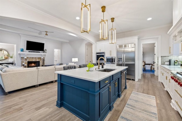 kitchen with a fireplace, white cabinets, built in appliances, blue cabinets, and tasteful backsplash