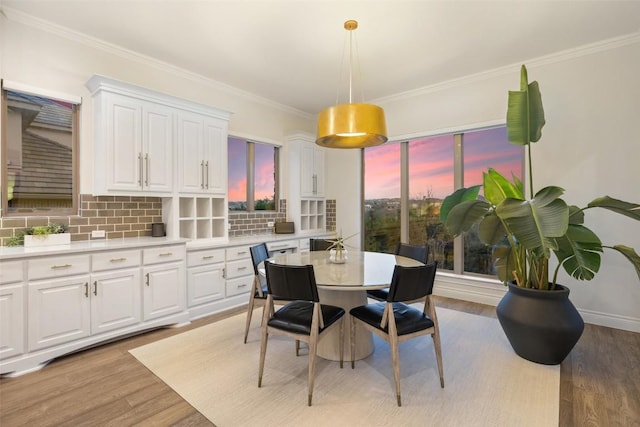 dining area with baseboards, light wood-style flooring, and ornamental molding