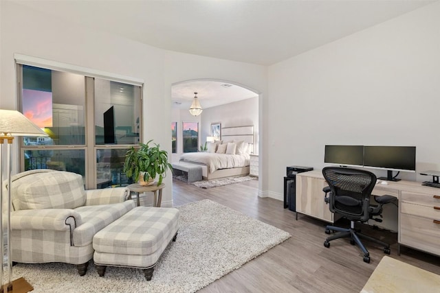 home office featuring wood finished floors, arched walkways, and baseboards