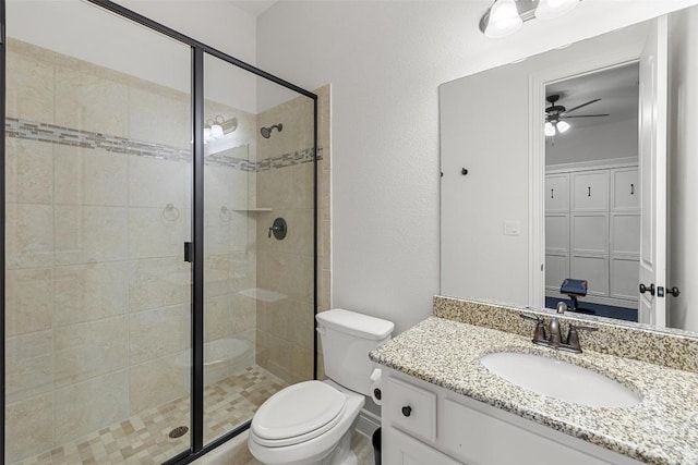 full bath featuring vanity, a shower stall, toilet, and a ceiling fan