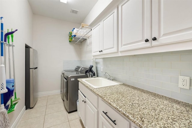 laundry room with light tile patterned floors, baseboards, visible vents, a sink, and washing machine and dryer