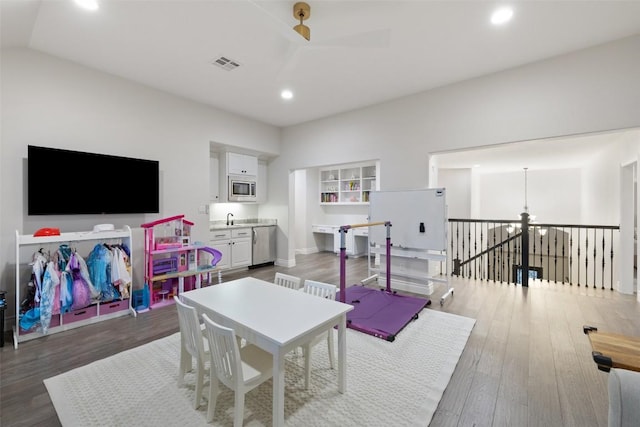 rec room with visible vents, recessed lighting, ceiling fan with notable chandelier, wood finished floors, and a sink