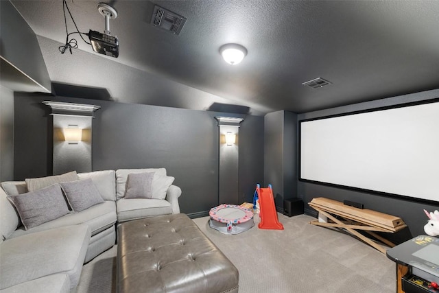 carpeted cinema room with vaulted ceiling, visible vents, and a textured ceiling