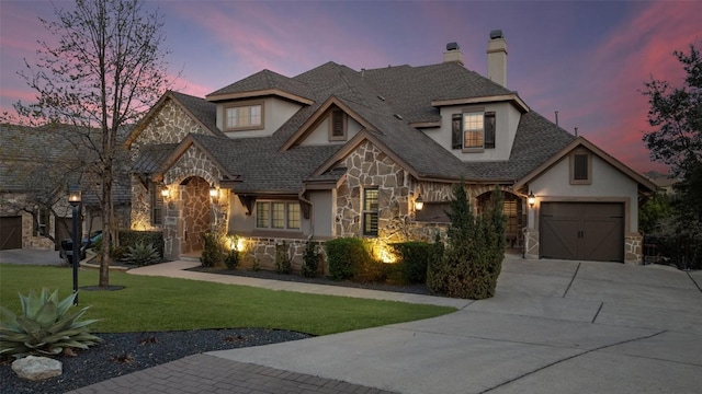 view of front facade with stucco siding, stone siding, a yard, concrete driveway, and a garage