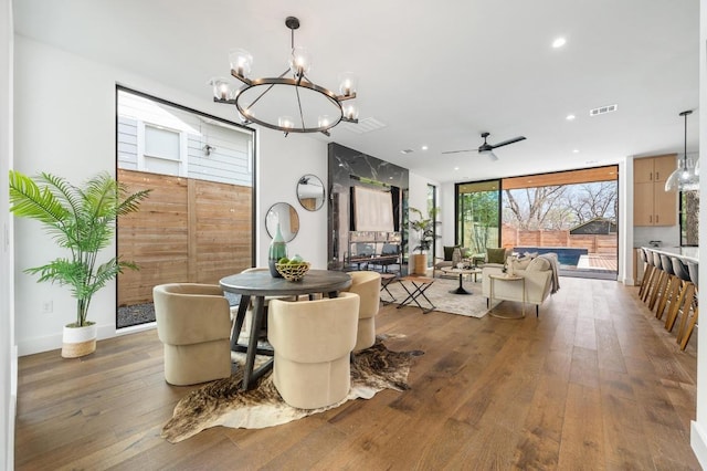 dining space featuring visible vents, recessed lighting, hardwood / wood-style flooring, expansive windows, and ceiling fan with notable chandelier