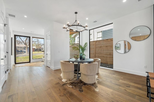 dining area with a wealth of natural light, a notable chandelier, visible vents, and hardwood / wood-style flooring