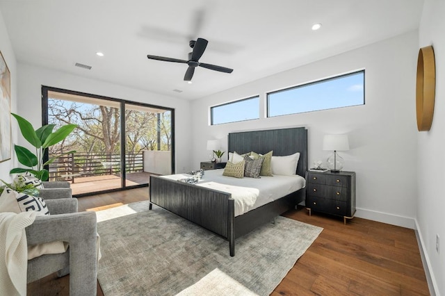 bedroom with visible vents, multiple windows, wood finished floors, and access to outside