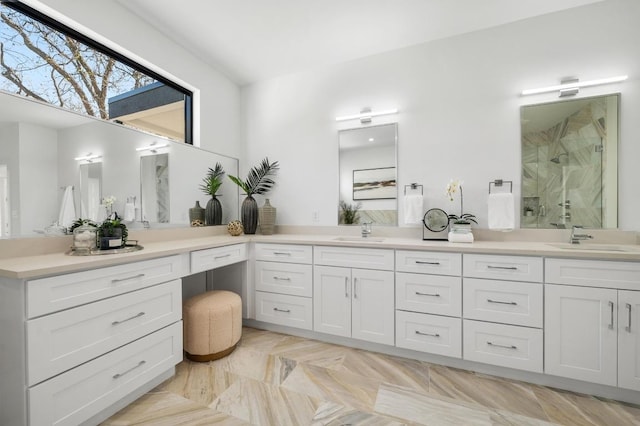 full bathroom featuring a sink, a marble finish shower, and double vanity