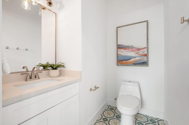 bathroom featuring toilet, vanity, and baseboards