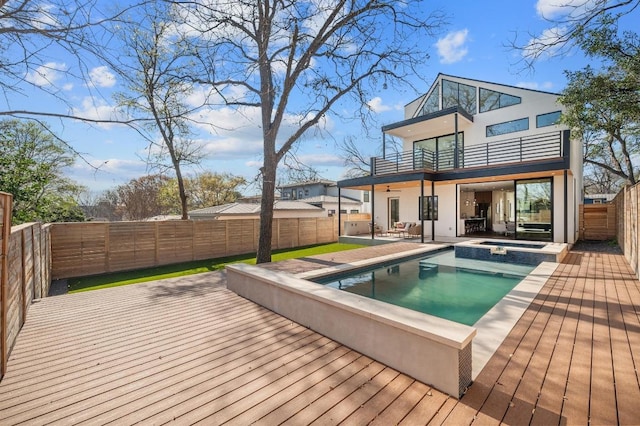 back of house featuring a pool with connected hot tub, stucco siding, a fenced backyard, a balcony, and a patio area