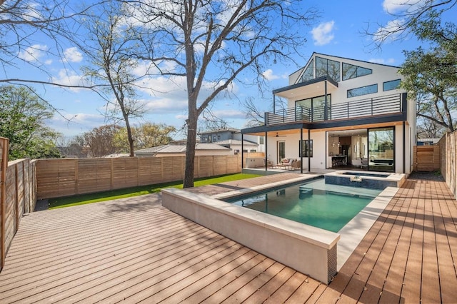 1608 Dexter St, Austin, TX 78704 - back of property featuring a balcony, a fenced backyard, a wooden deck, stucco siding, and a pool with connected hot tub