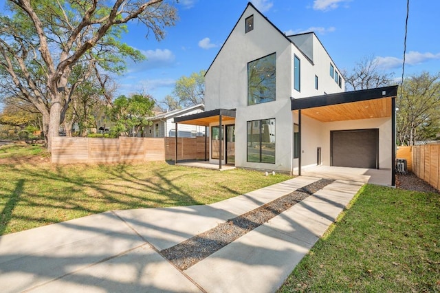 contemporary house featuring a front yard, fence, driveway, an attached garage, and stucco siding