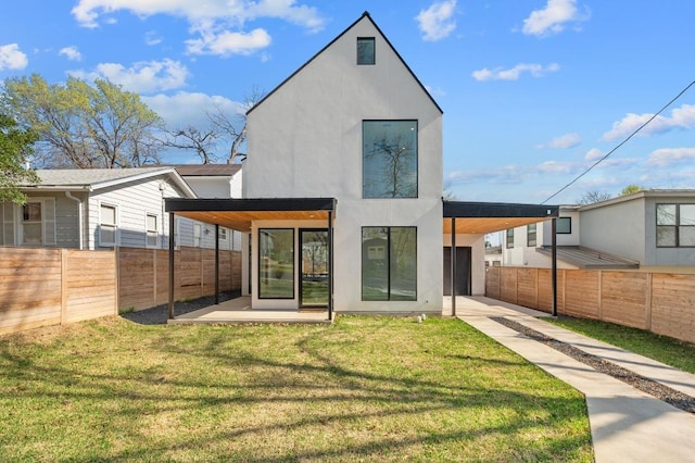 rear view of house with stucco siding, driveway, a yard, an attached carport, and fence private yard