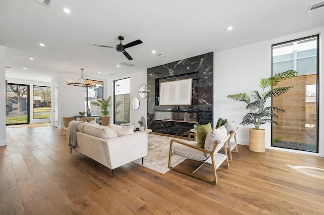 living room featuring recessed lighting, visible vents, ceiling fan with notable chandelier, and wood finished floors