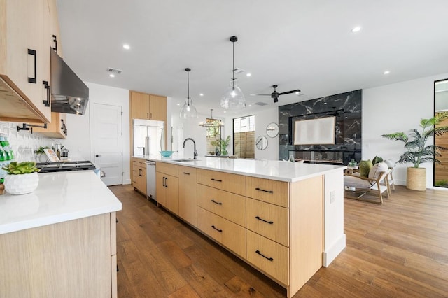 kitchen with built in refrigerator, light brown cabinetry, a sink, light countertops, and extractor fan