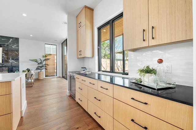 kitchen with decorative backsplash, wine cooler, light brown cabinets, and hardwood / wood-style flooring