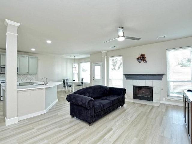 living room with visible vents, a healthy amount of sunlight, a fireplace, and a ceiling fan