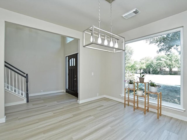 foyer entrance with stairway, light wood-style floors, visible vents, and baseboards