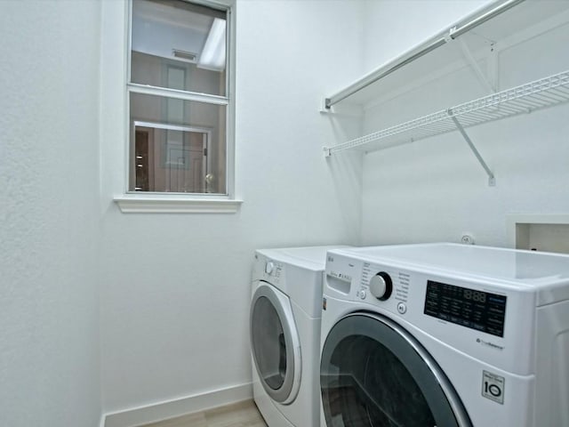 laundry room featuring light wood finished floors, visible vents, baseboards, washing machine and dryer, and laundry area