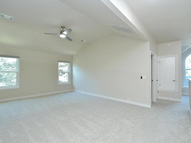 empty room with visible vents, light colored carpet, lofted ceiling, and ceiling fan