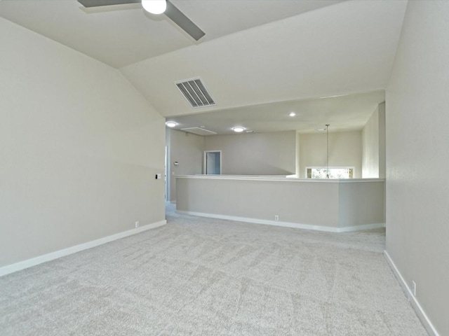 carpeted empty room with baseboards, visible vents, attic access, lofted ceiling, and ceiling fan