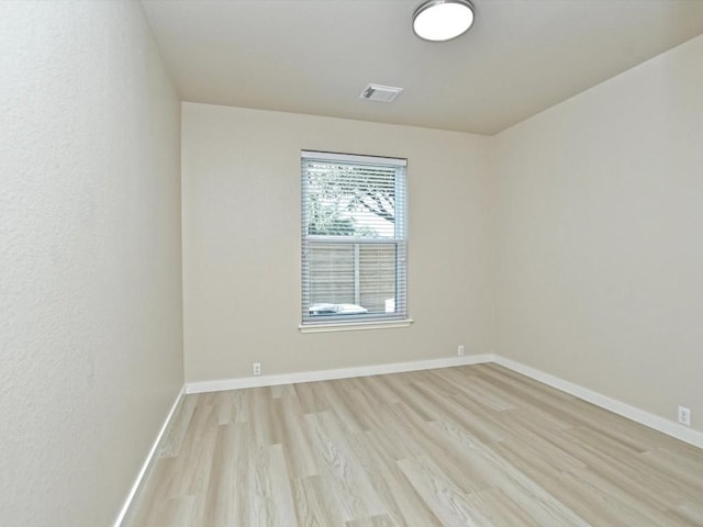 unfurnished room with visible vents, light wood-style flooring, and baseboards