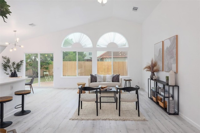 living area featuring a notable chandelier, visible vents, high vaulted ceiling, and light wood-type flooring