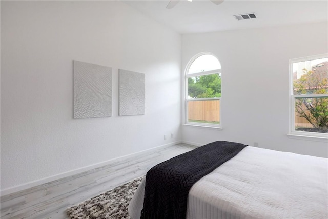 bedroom with a ceiling fan, wood finished floors, baseboards, and visible vents