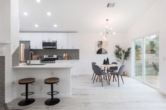 kitchen featuring visible vents, a sink, stainless steel appliances, a breakfast bar area, and decorative backsplash