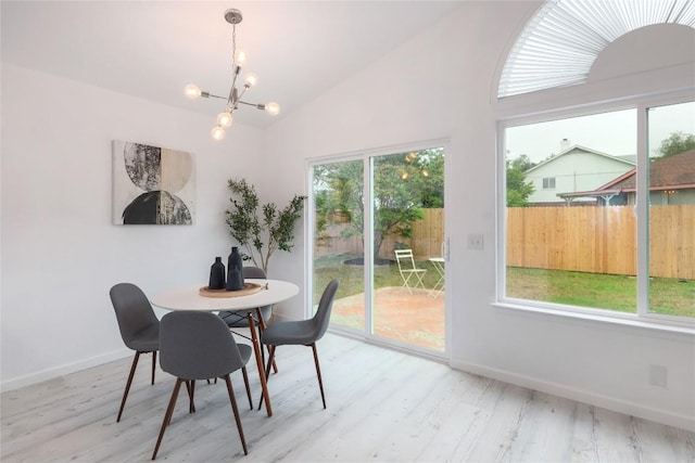 dining area featuring a chandelier, wood finished floors, baseboards, and vaulted ceiling