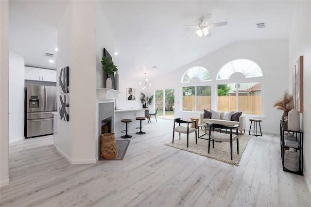 interior space featuring visible vents, ceiling fan, a tiled fireplace, lofted ceiling, and light wood-style flooring