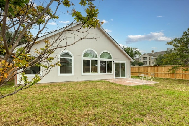 rear view of property with a yard, stucco siding, a patio, and fence