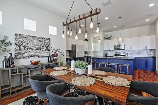 dining room featuring recessed lighting, visible vents, dark wood-type flooring, and a towering ceiling