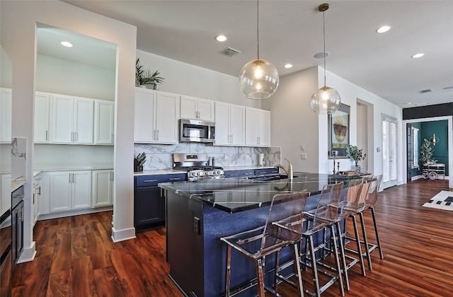 kitchen featuring visible vents, a breakfast bar area, stainless steel appliances, and a sink