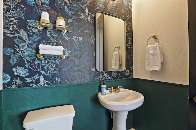 half bath with toilet and wallpapered walls