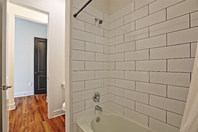 full bath featuring bathtub / shower combination, toilet, wood finished floors, and baseboards