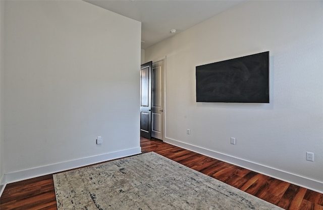 empty room featuring dark wood-style floors and baseboards